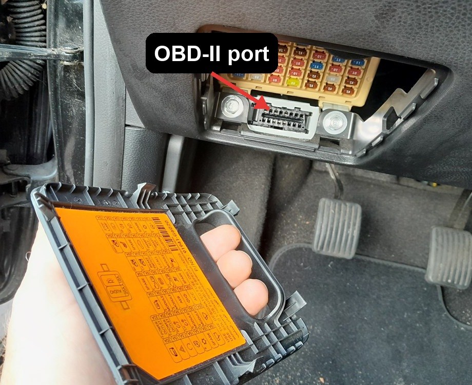 OBD-II port location on a Kia Picanto (JA, 2017-present), low on the driver's side just below the cabin fuse panel behind a pull-off cover